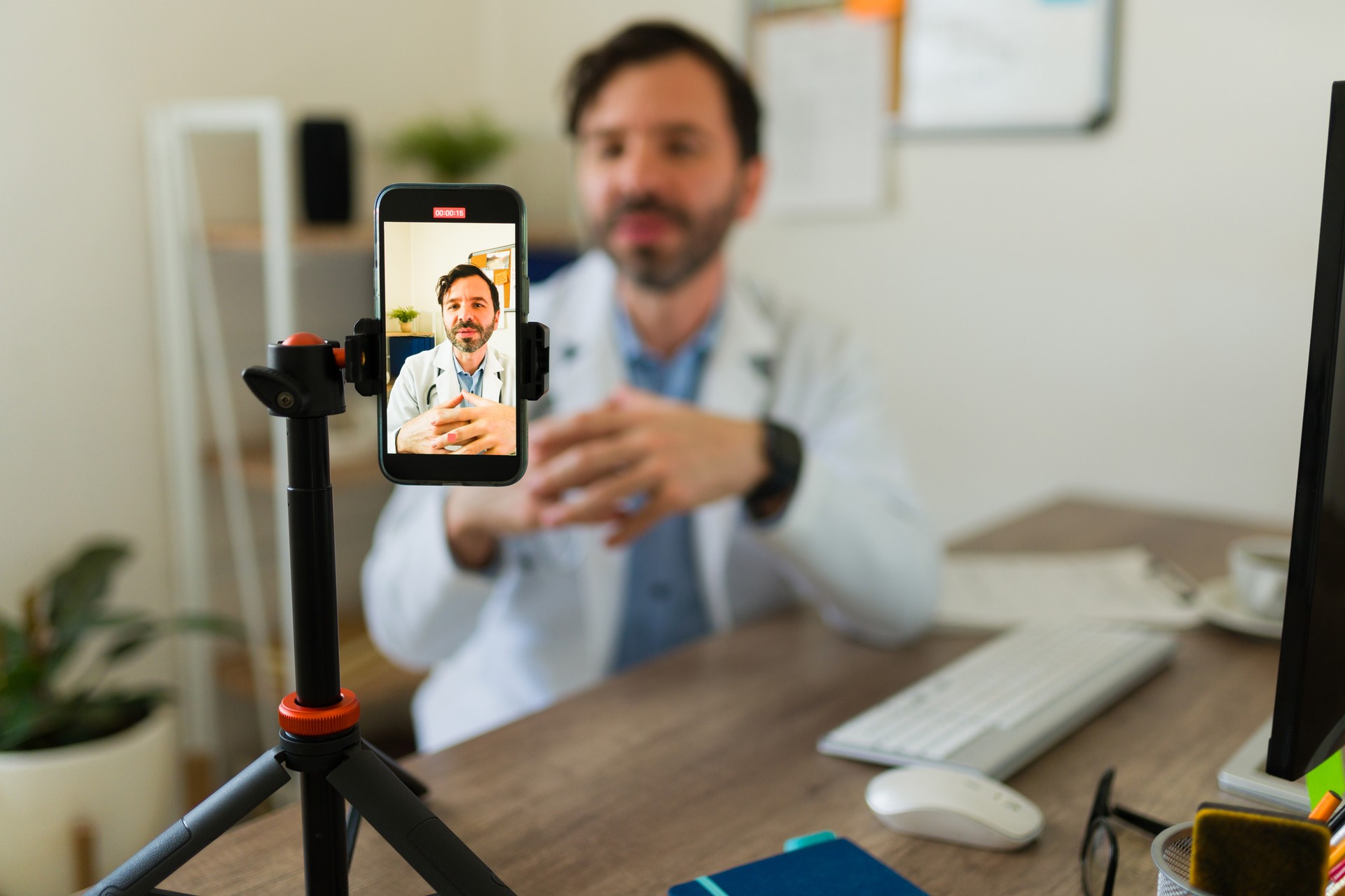 Hispanic doctor streaming using his smartphone or filming an online video for his patients or social media while at the office